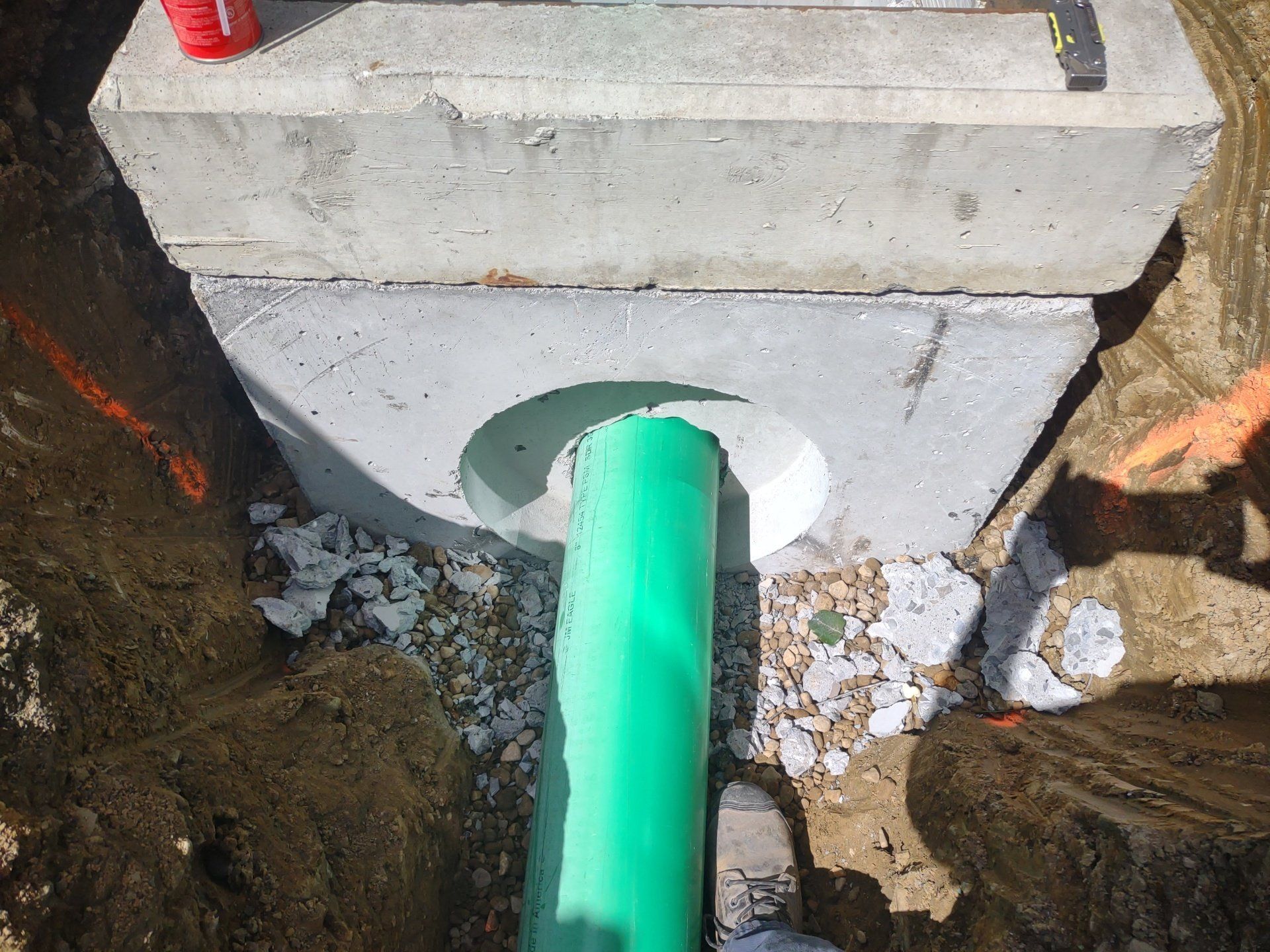 A green pipe is coming out of a hole in the ground