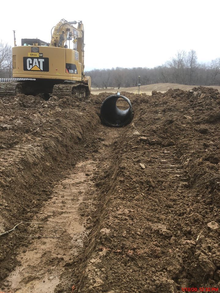 A cat excavator is digging a hole in the dirt