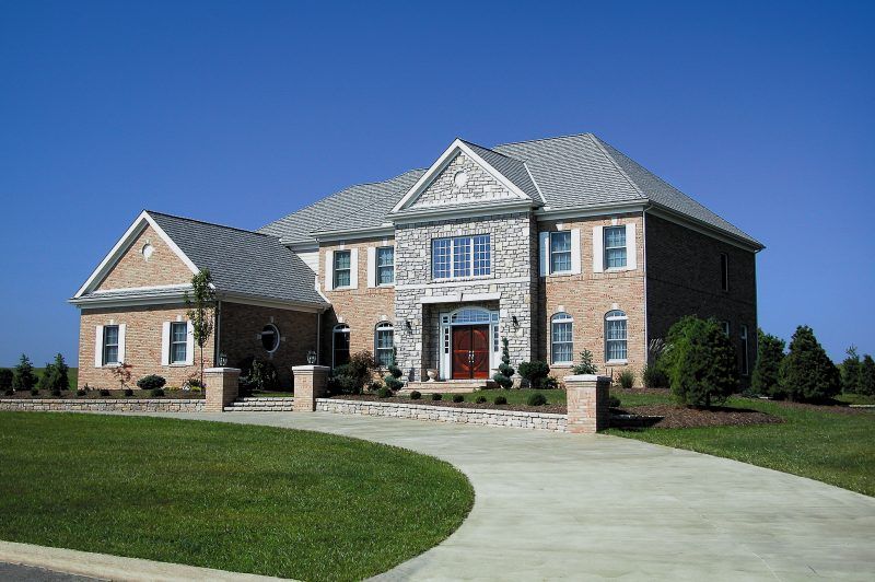 A large brick house with a concrete driveway in front of it