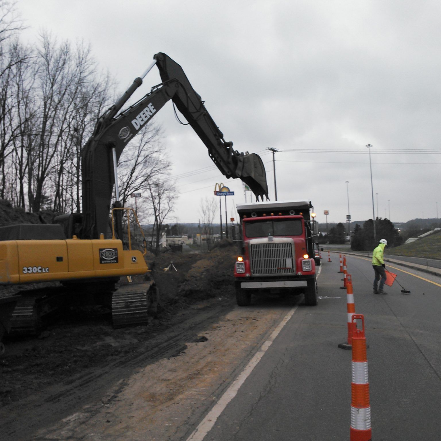 A yellow deere excavator is working on a road