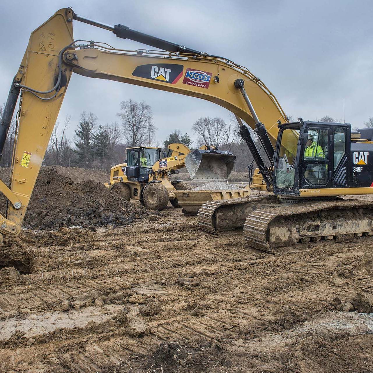A cat excavator is digging a hole in the dirt.