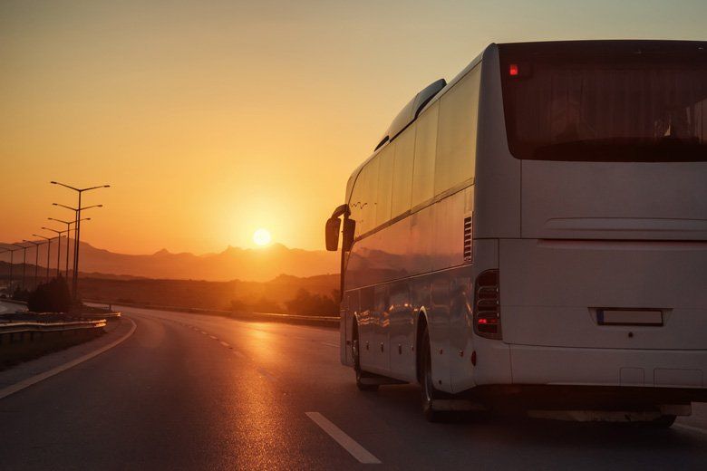White Bus Driving on Road Towards the Sunset — Coaches in Coffs Harbour, NSW