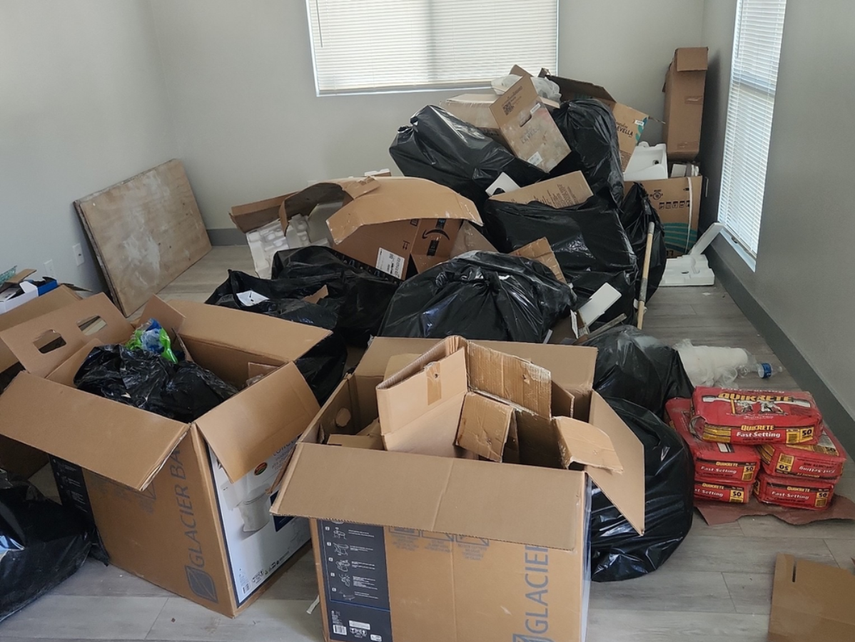 A room filled with cardboard boxes and black trash bags; likely debris.
