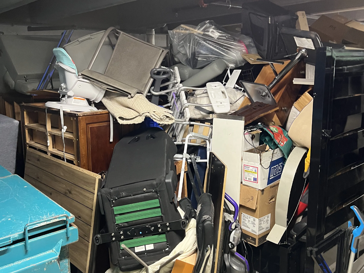 Messy storage area filled with furniture, boxes, and various items. Overstuffed, with a blue container visible.