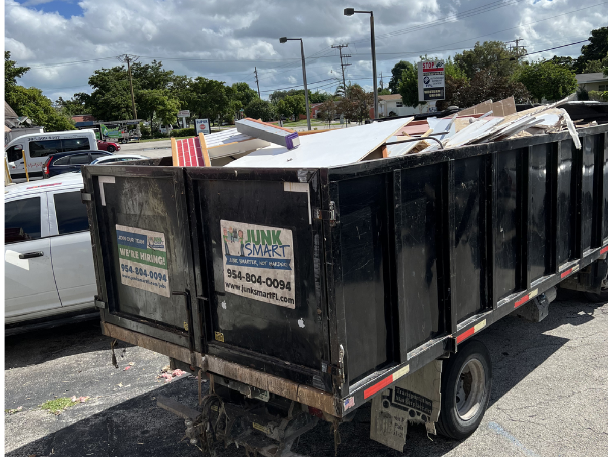 Black dump truck filled with construction debris, parked in a lot.