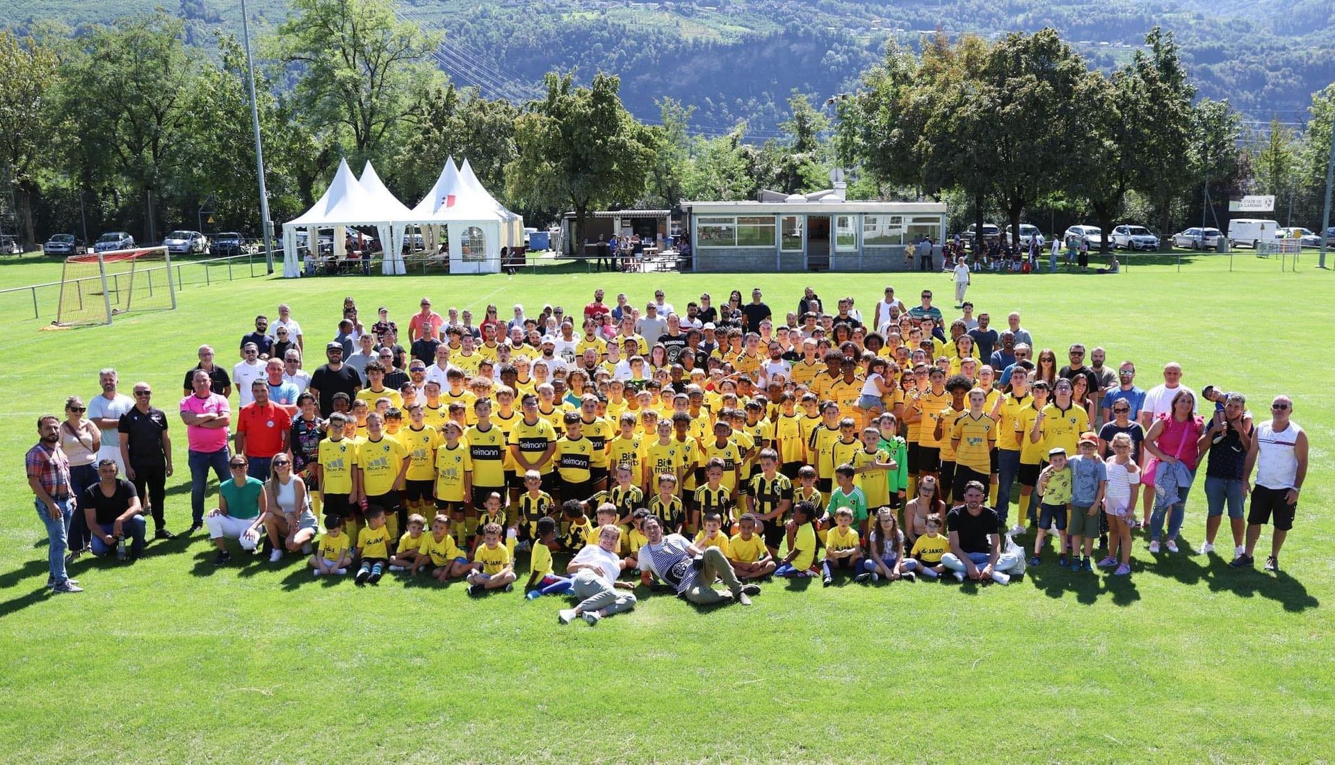 Un grand groupe de personnes pose pour une photo dans un champ.