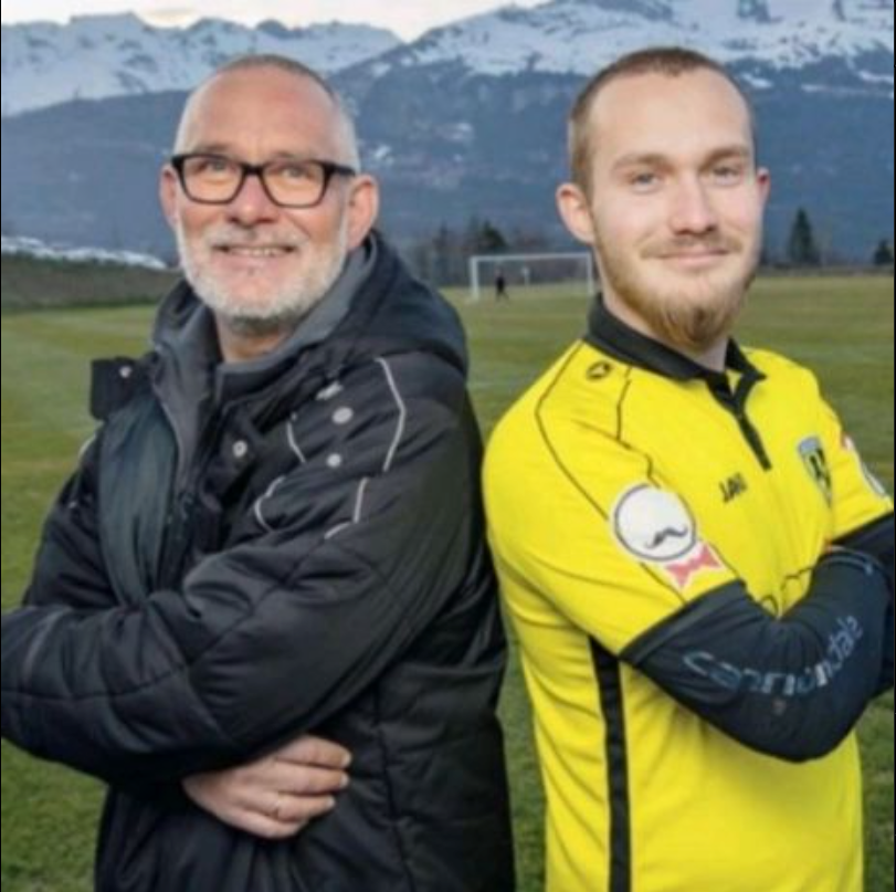 Un homme portant une veste noire se tient à côté d'un homme portant une chemise jaune