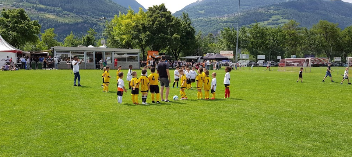 Un groupe d'enfants jouent au football sur un terrain.