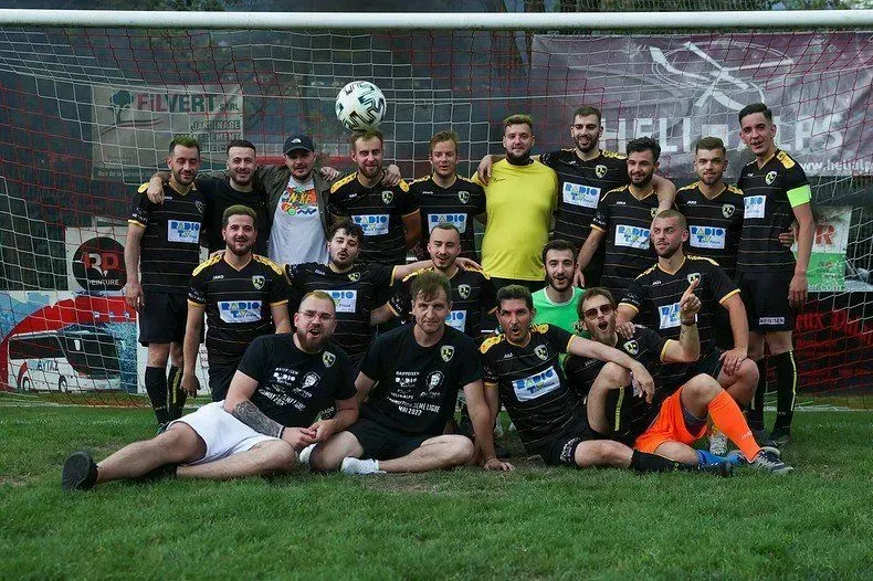 Un groupe d'hommes pose pour une photo sur un terrain de football.