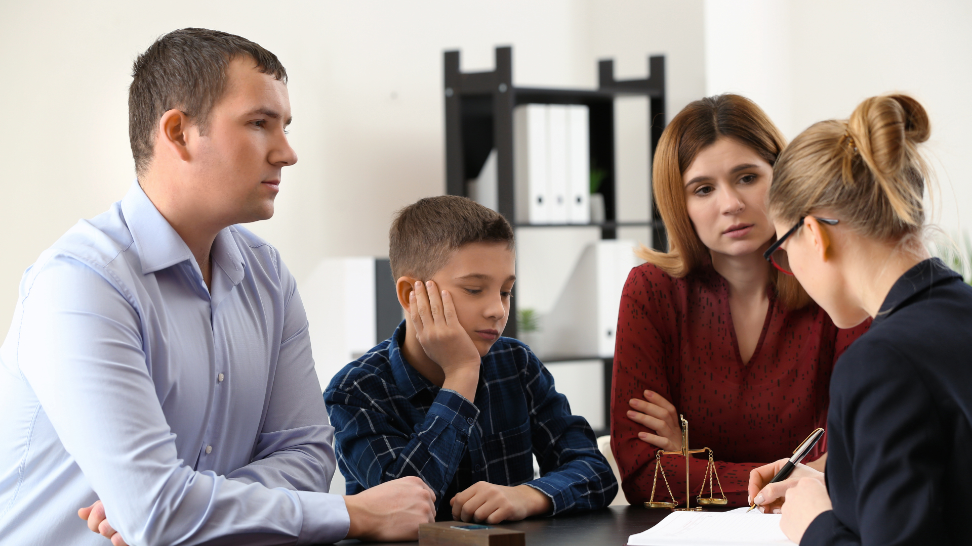 Four people in a meeting, discussing papers at a table in an office.