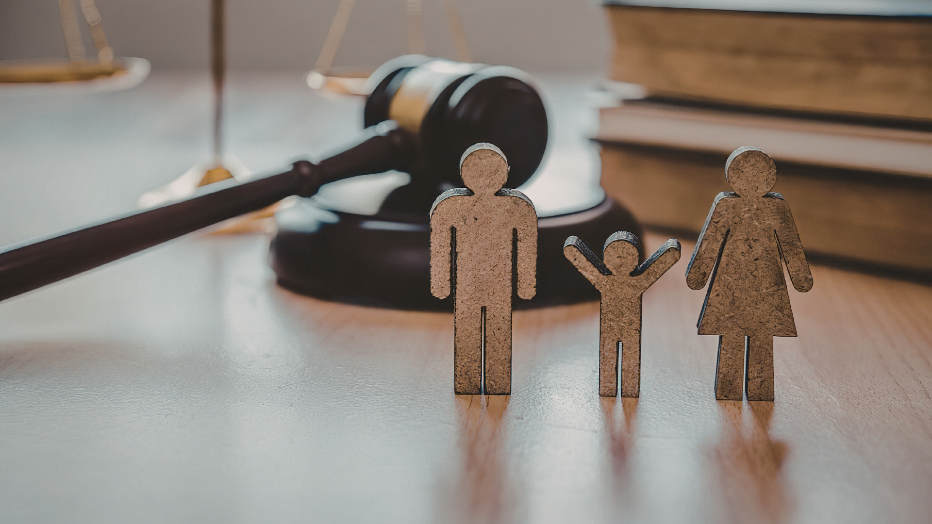 Miniature family figures beside a judge’s gavel on a desk, suggesting family law or custody.