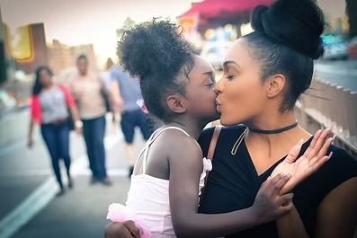 Two people kissing on a street, with a blurred crowd in the background.