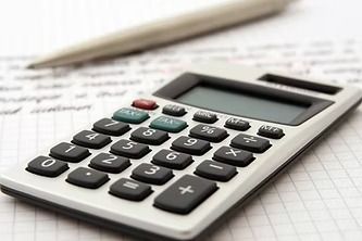 Calculator on graph paper with a pen in the background