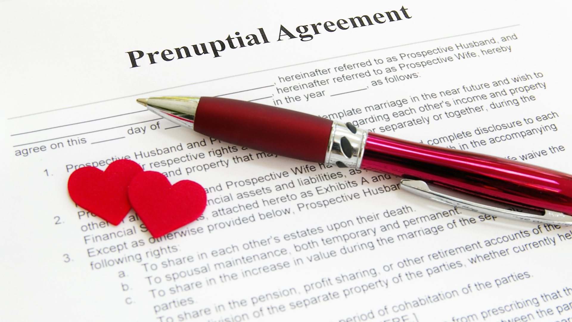 Red pen and red hearts on a prenuptial agreement document