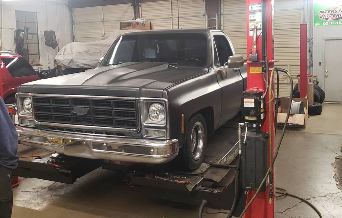 A black Chevrolet pickup truck on a lift inside a garage | Gateway Automotive Inc.