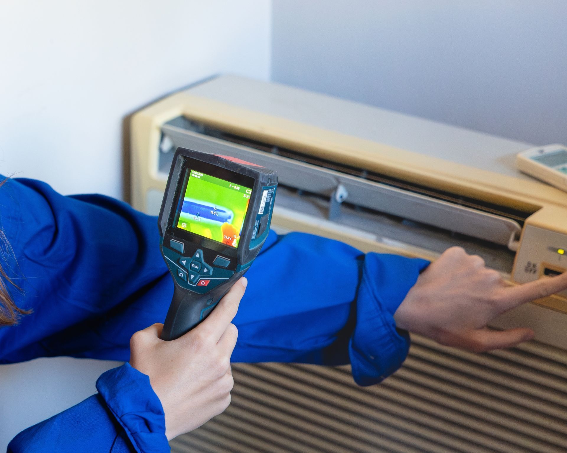 Thermal camera checking a blue-clad arm near a wall-mounted heating unit