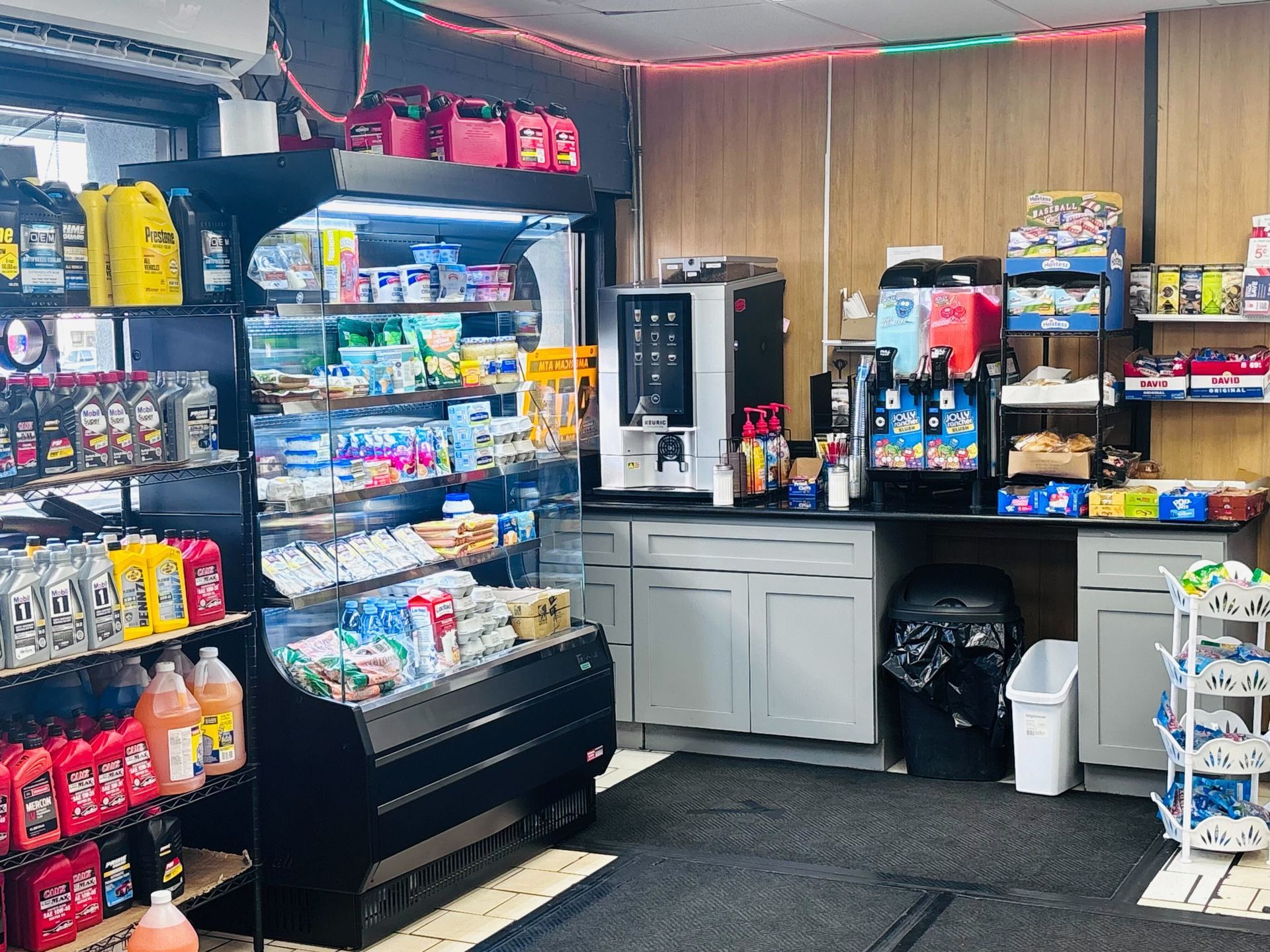 Interior of a convenience store with shelves of goods, coffee machines, and a cooler.