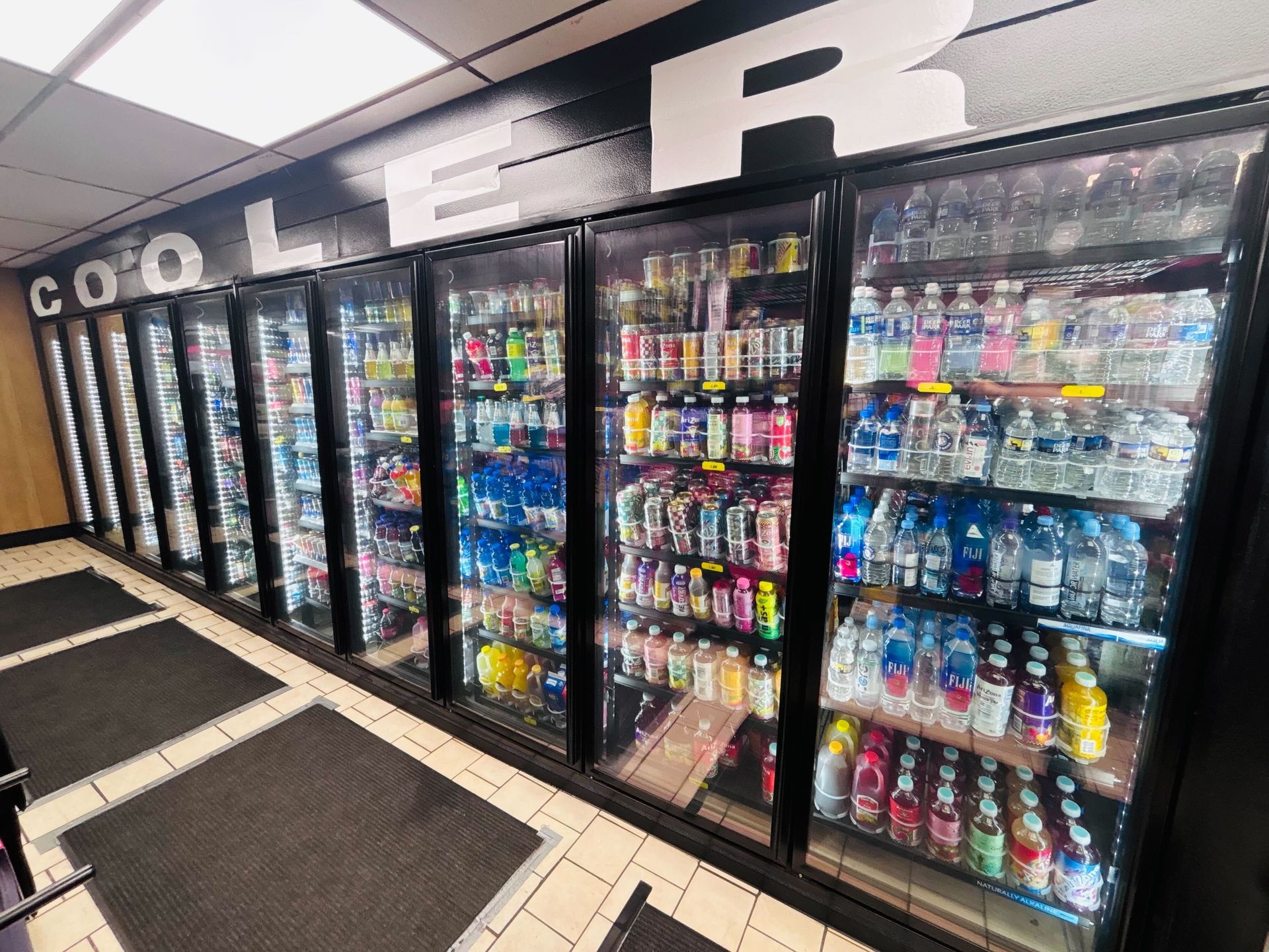 Refrigerated beverage coolers in a convenience store. Sodas and waters are stocked behind glass doors.