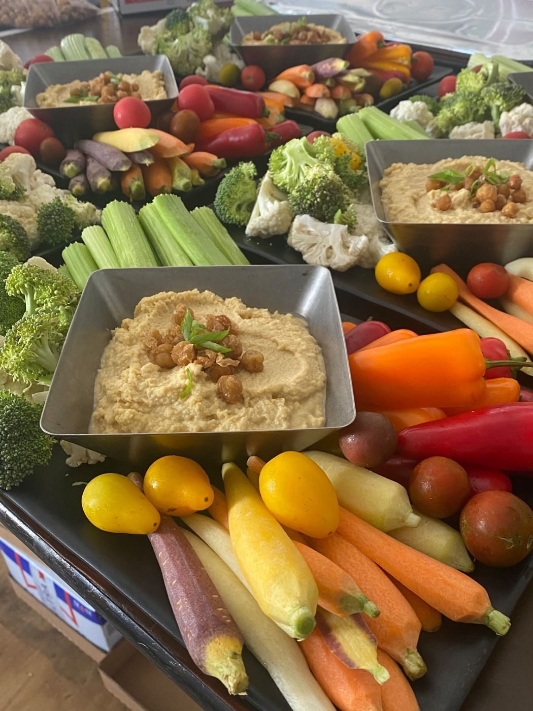 Vegetable platter with hummus. Colorful carrots, peppers, broccoli, cauliflower, celery, and tomatoes.