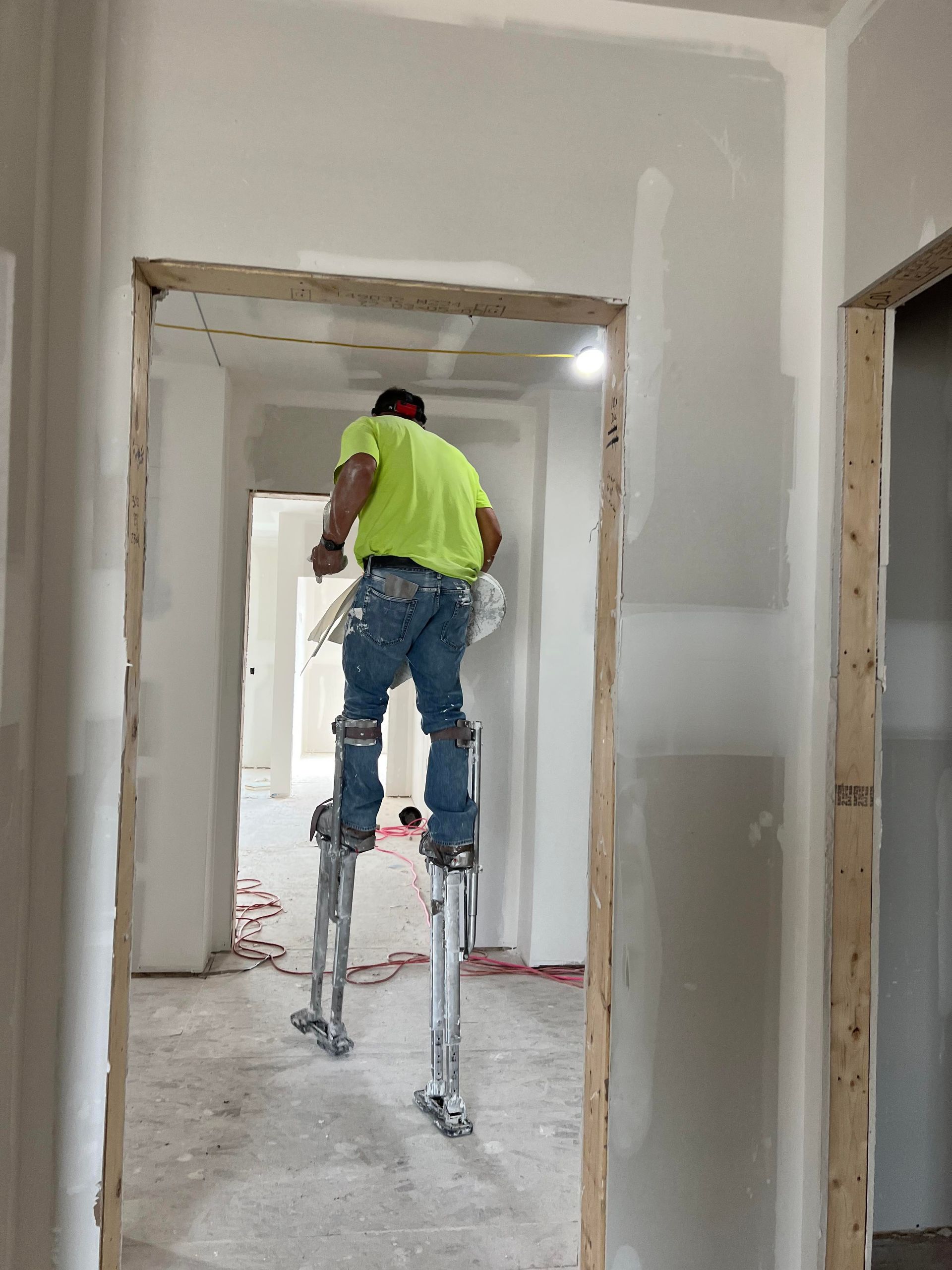 A man is standing on stilts in a hallway.