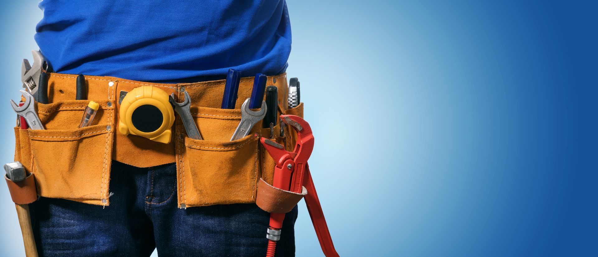 A person wearing a blue shirt and jeans with a tool belt.