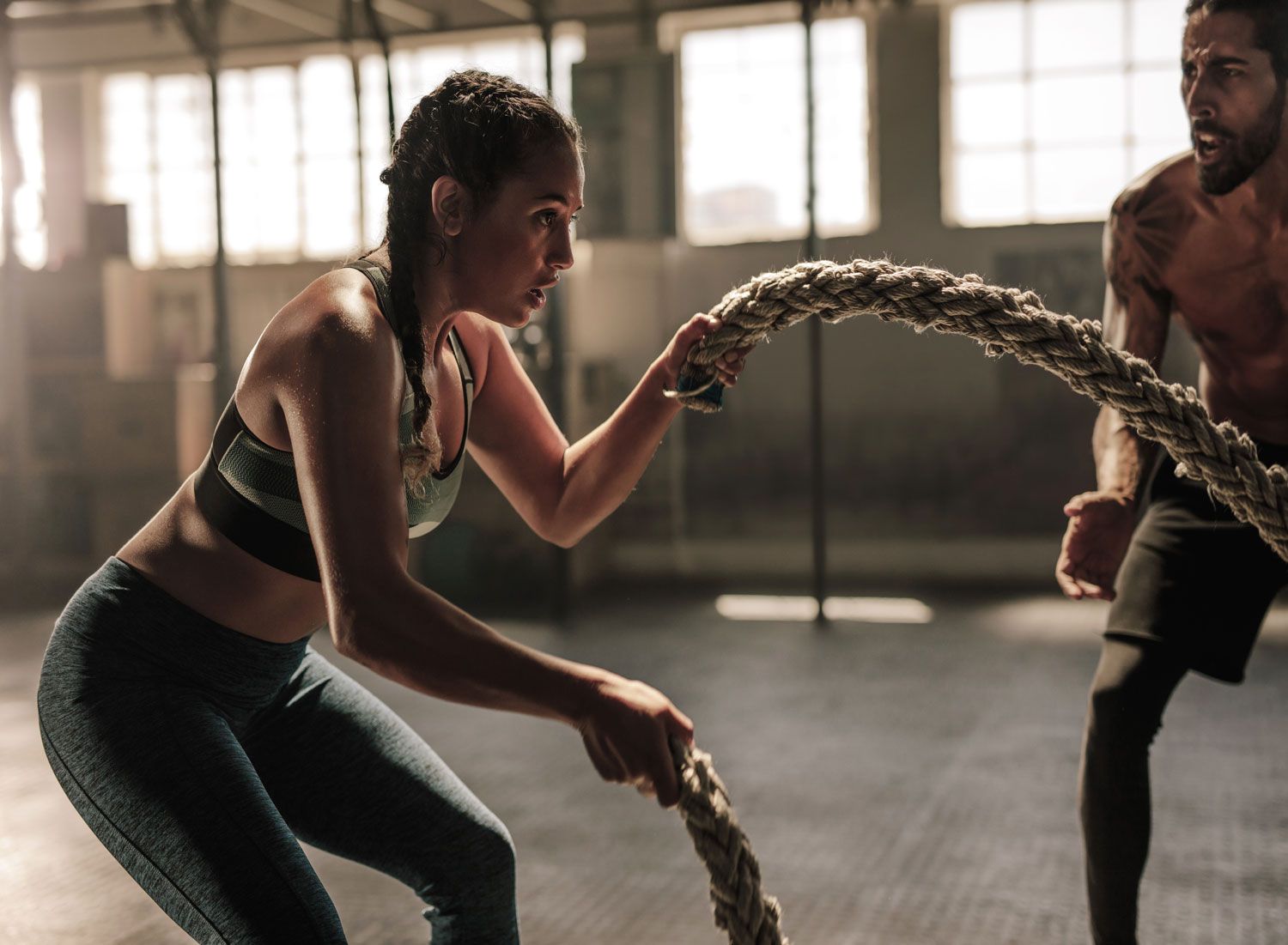 strong-woman-exercising-with-battle-ropes-at-the-gym-with-male-trainer-athlete-doing-battle-rope