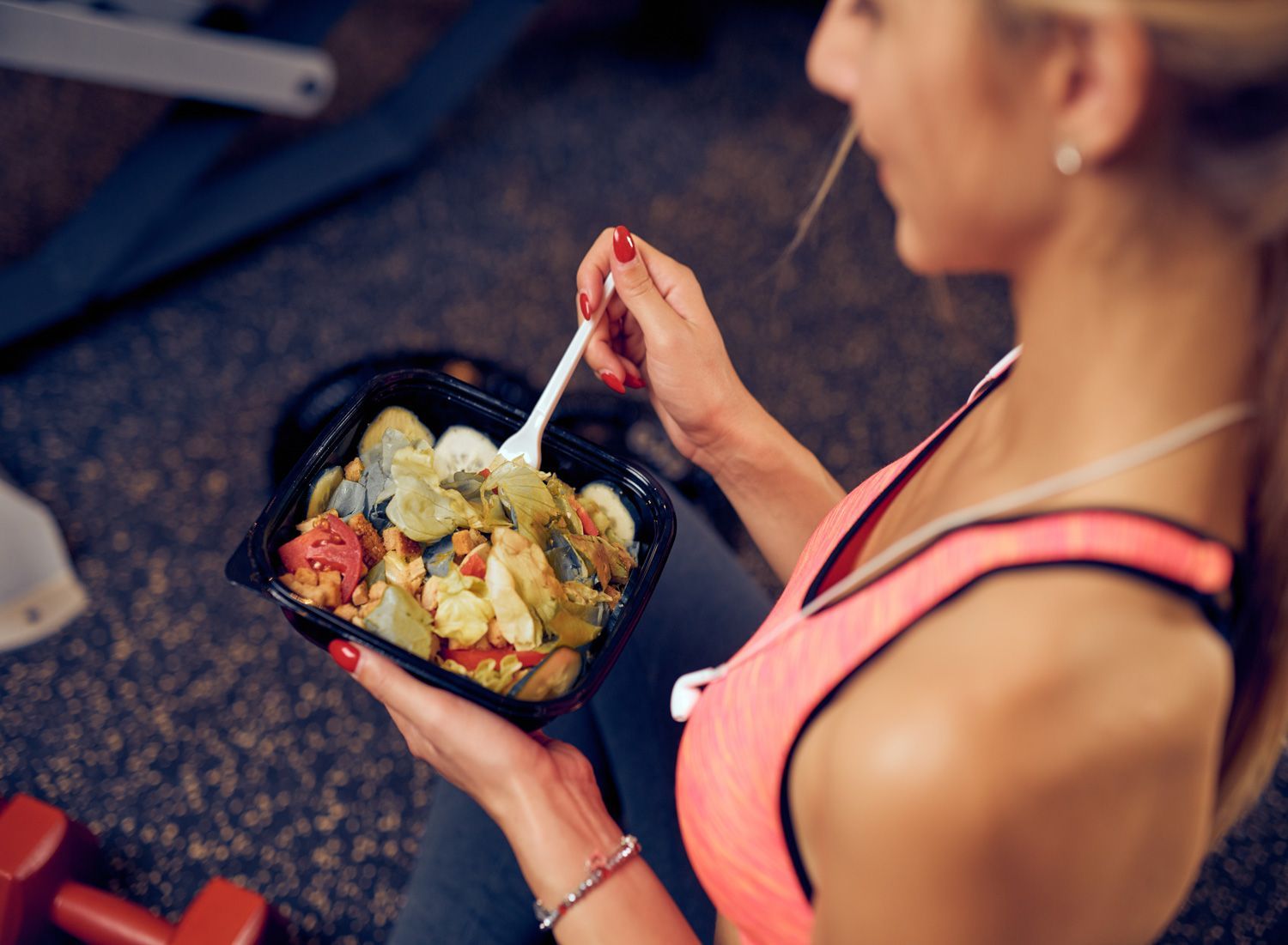 top-view-of-woman-eating-healthy-food-while-sitting-in-a-gym-heatlhy-lifestyle-concept