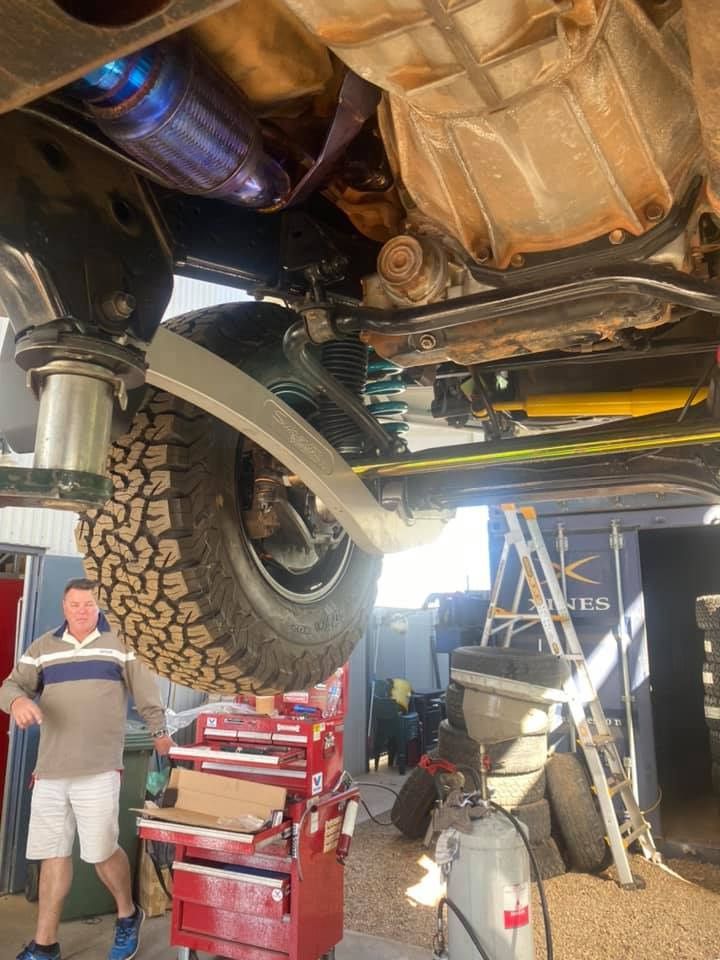 A Man is Standing Underneath a Truck in a Garage — RK Diesel Services in Modbury, SA