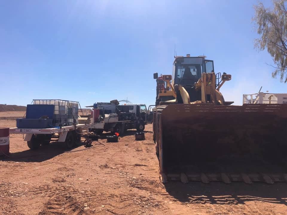 A Bulldozer is Parked Next to a Truck in a Dirt Field — RK Diesel Services in Ciccone, NT