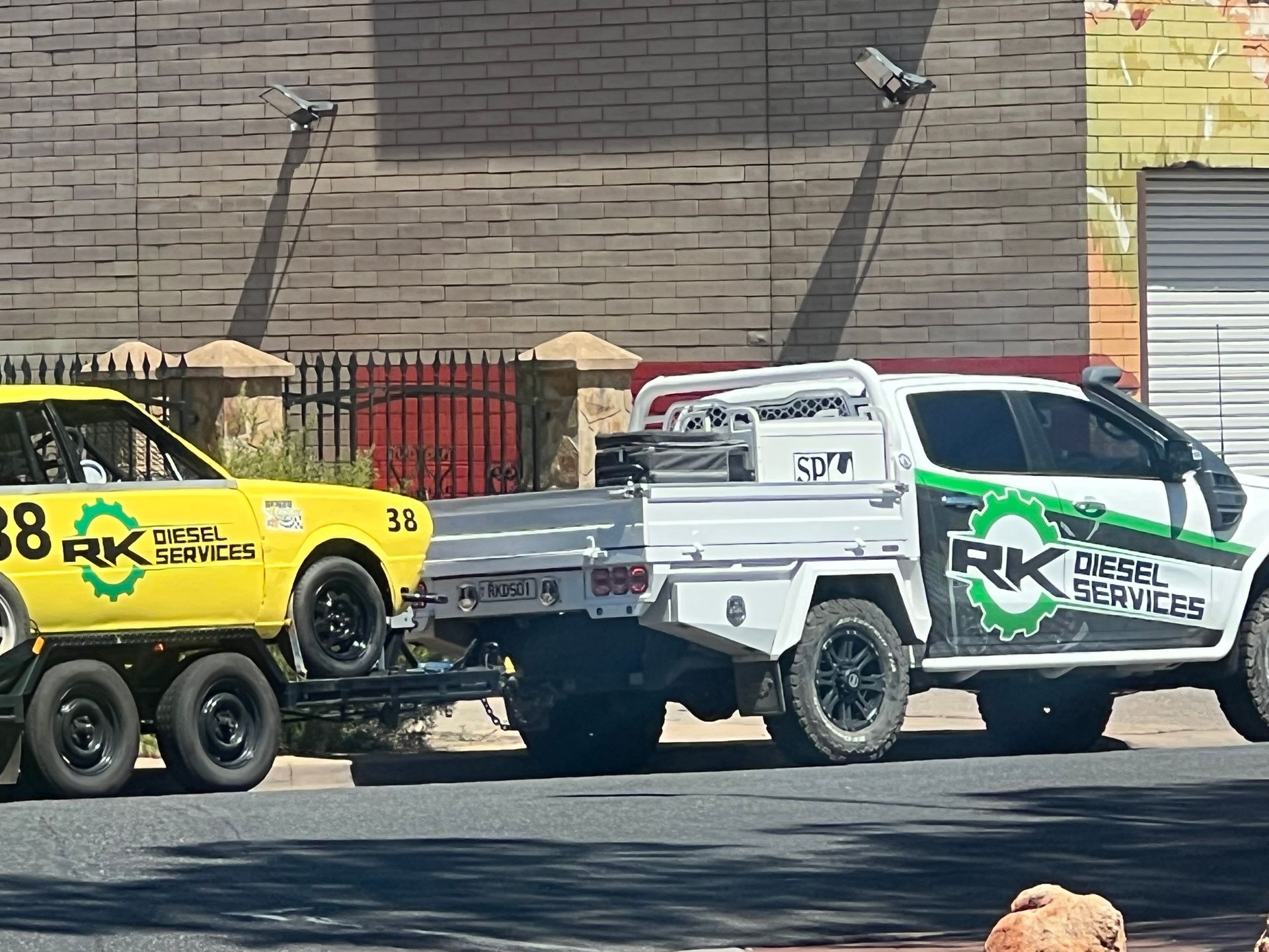 White truck towing a yellow race car with 