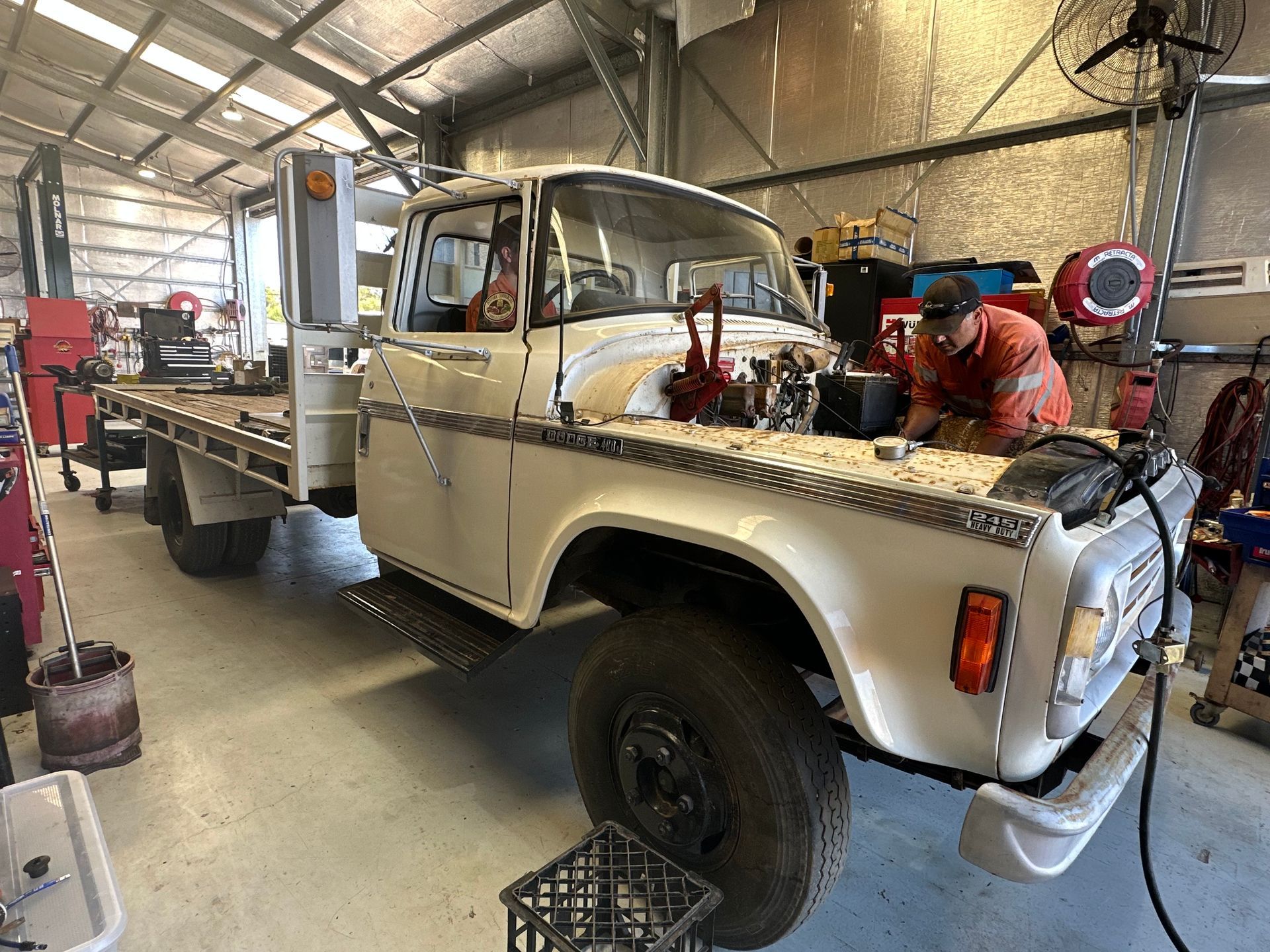 White pickup truck being worked on in a garage. Mechanic in orange coveralls leans over the open hood. — RK Diesel Services in Ciccone, NT