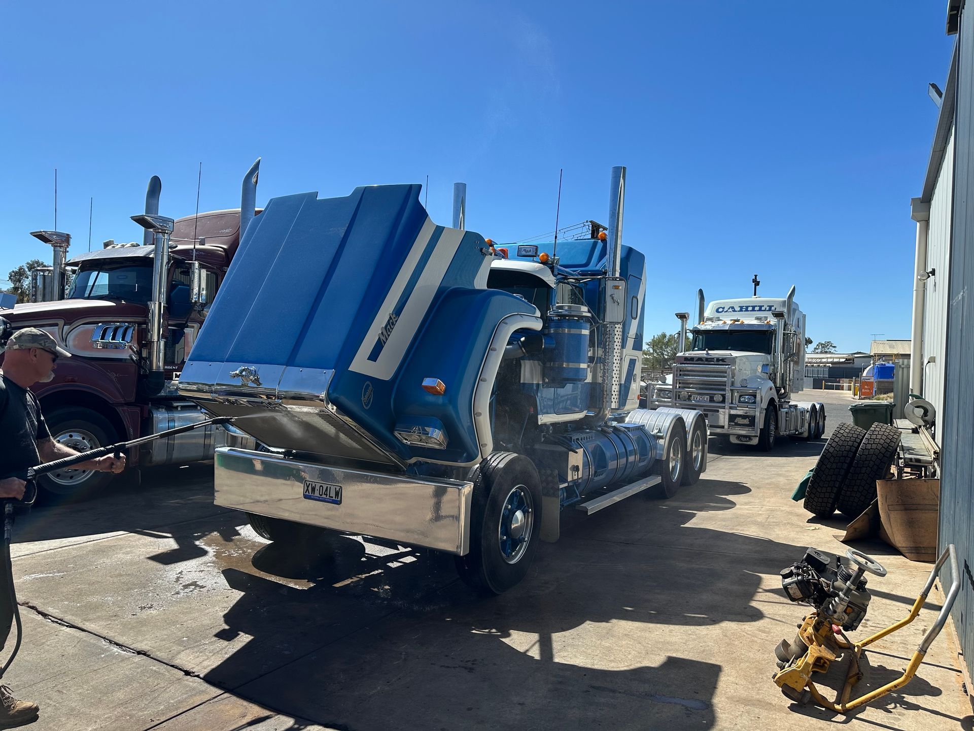 Blue semi-truck with open hood; another truck nearby. Outdoor setting. — RK Diesel Services in Ciccone, NT