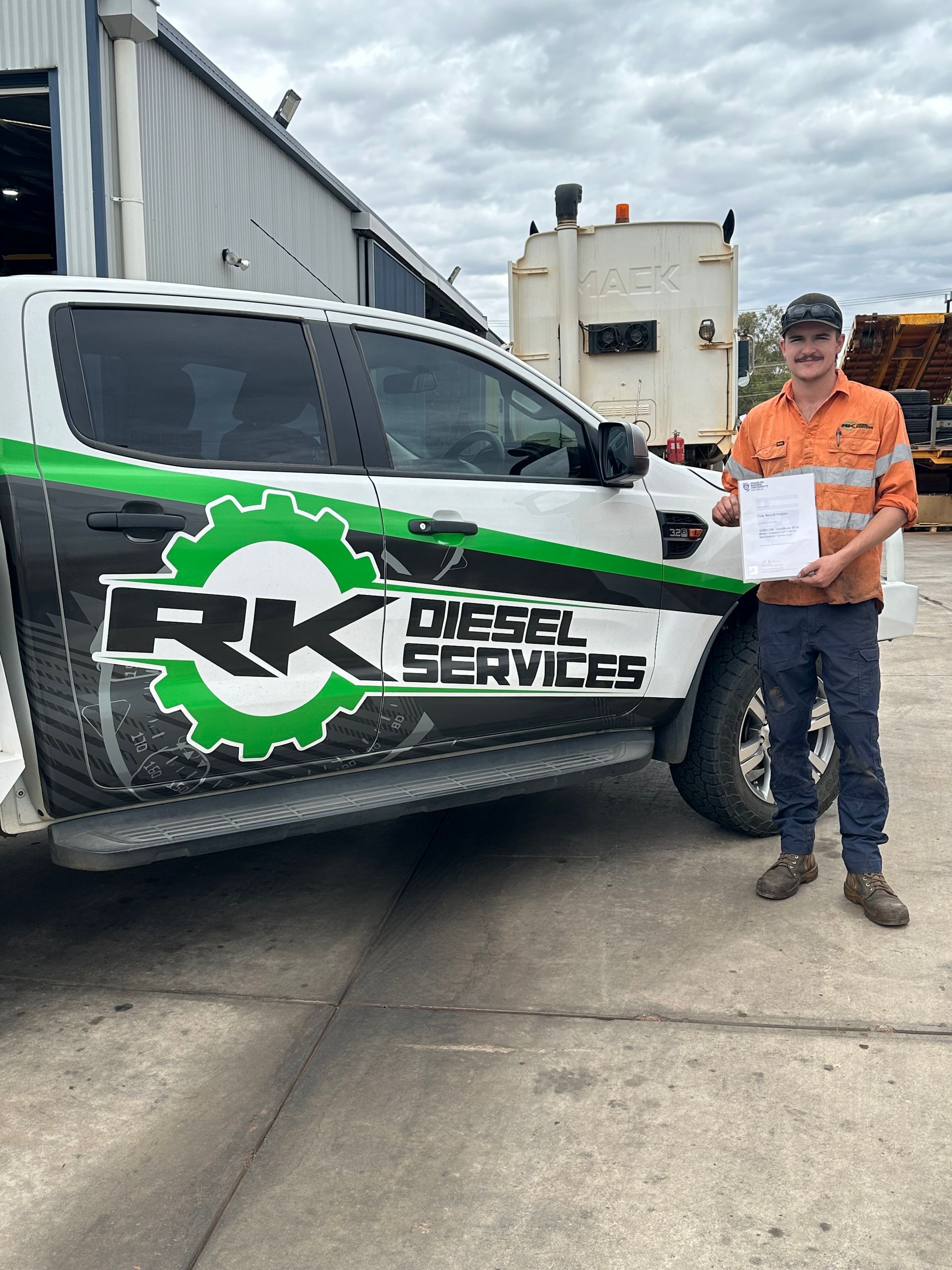 Man in work clothes standing by a white truck with 