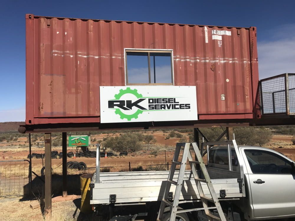 A Truck is Parked in Front of a Red Shipping Container — RK Diesel Services in Ciccone, NT