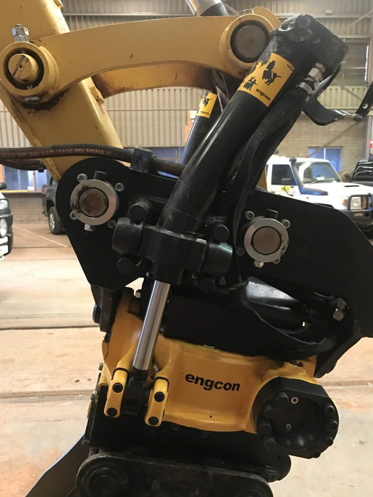 A Yellow and Black Excavator is Sitting in a Garage — RK Diesel Services in Ciccone, NT