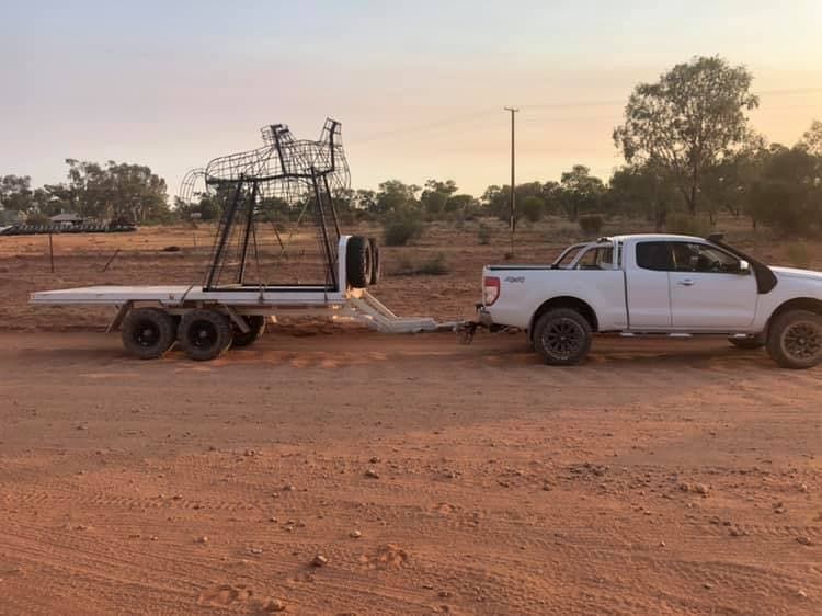 A White Truck is Towing a Trailer in a Dirt Field — RK Diesel Services in Ciccone, NT