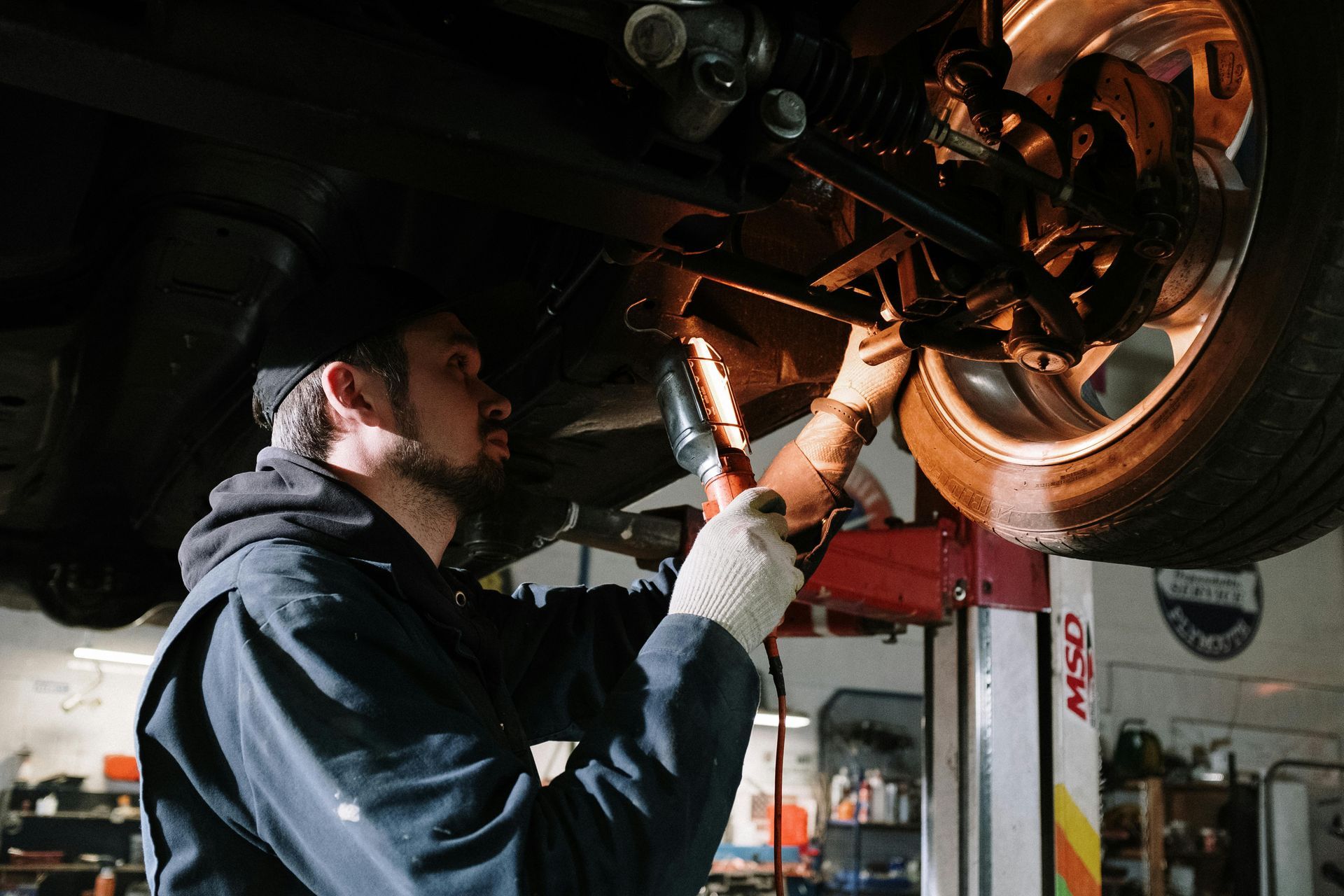 A man is working on the underside of a car in a garage.