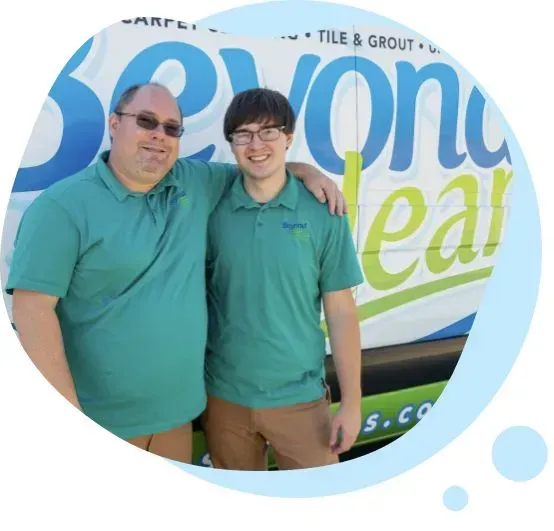 Two men are posing for a picture in front of a van that says beyond leaf