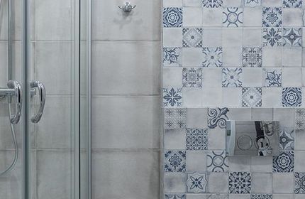 A bathroom with blue and white tiles and a shower stall.