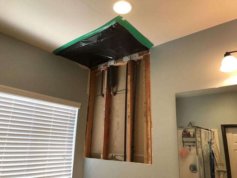 A bathroom with a hole in the ceiling and a window