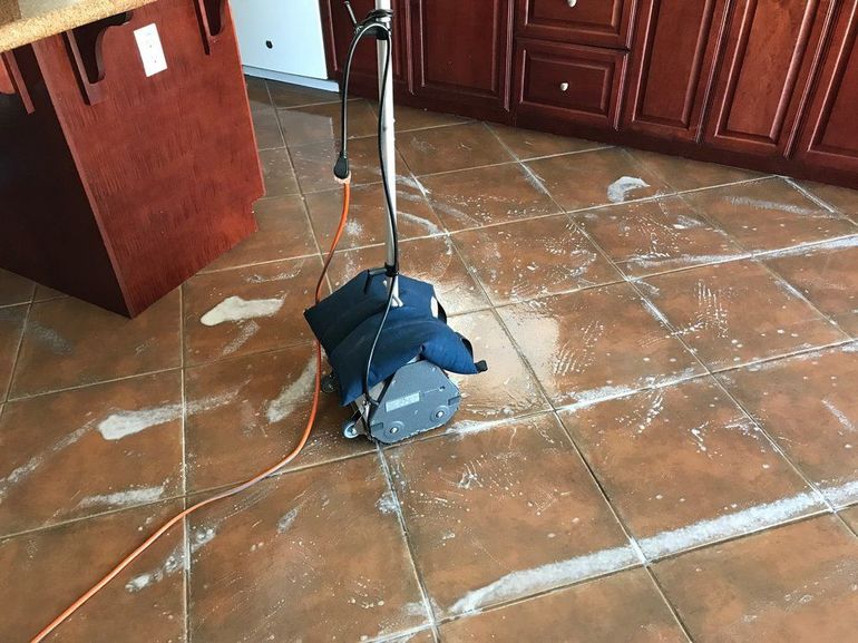 A vacuum cleaner is sitting on a tiled floor in a kitchen