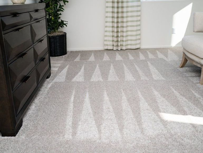 A living room with a dresser , chair , rug and carpet.