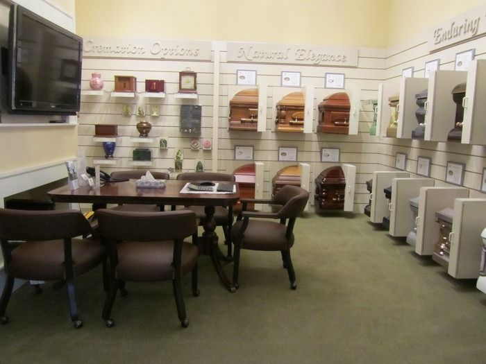 A funeral home showroom featuring shelves of cremation urns and displays of various wooden and metal caskets.