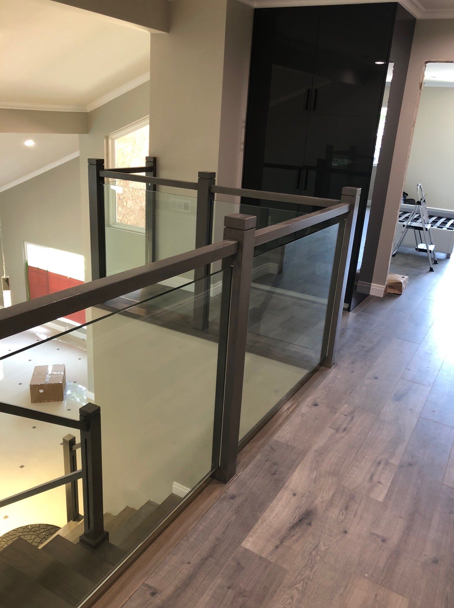 Interior view of a staircase with a modern glass and metal railing, natural light.