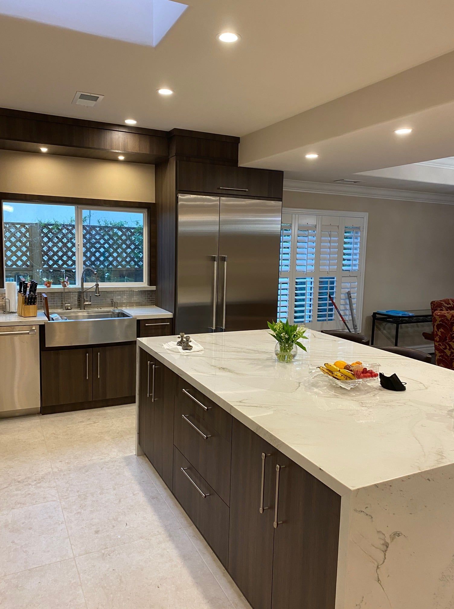 Modern kitchen with island, stainless steel appliances, and dark wood cabinets.
