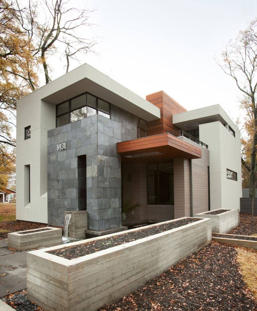 Modern two-story home with gray stone and light-colored walls, wood accents, and water feature.