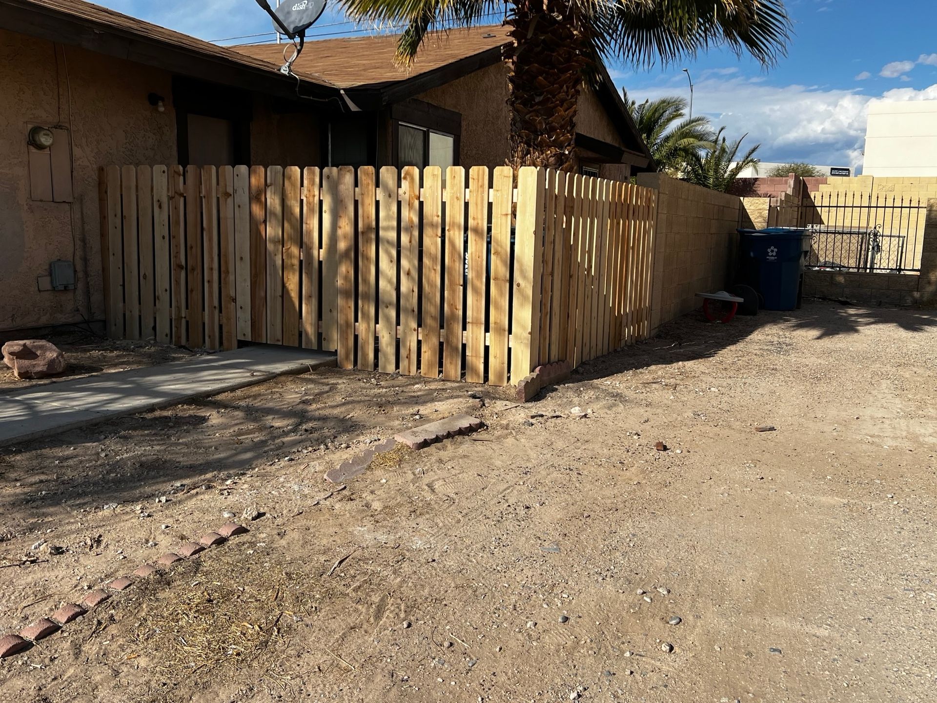 A wooden fence is in front of a house.