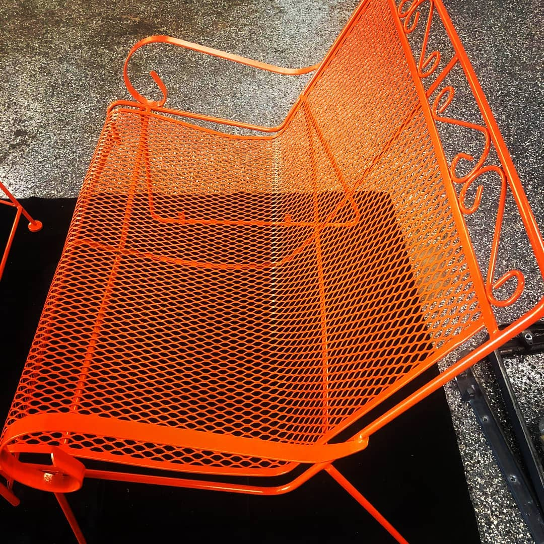 Orange metal patio chair with mesh seat.