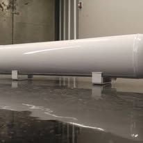 White, cylindrical object on two small, white rectangular supports, resting on a reflective, dark surface.