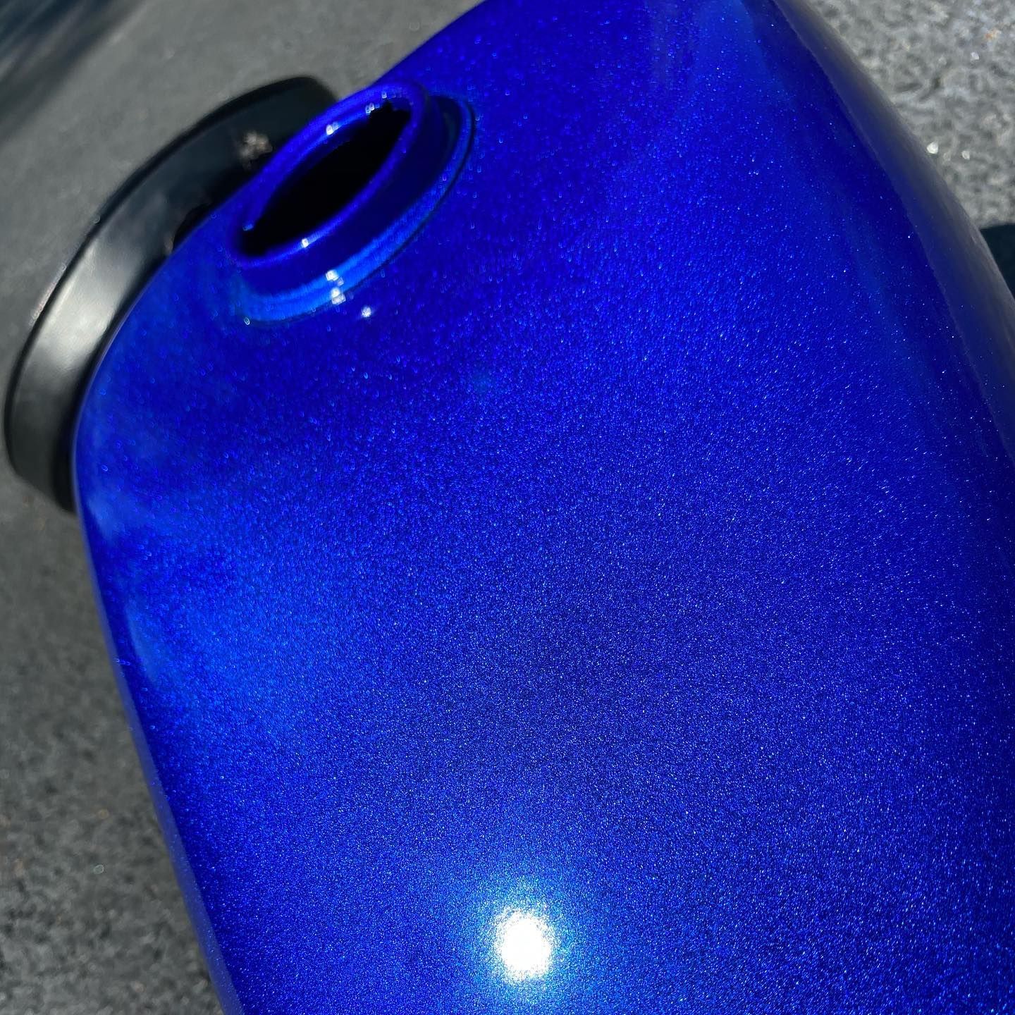 Blue metallic painted motorcycle gas tank with filler opening.